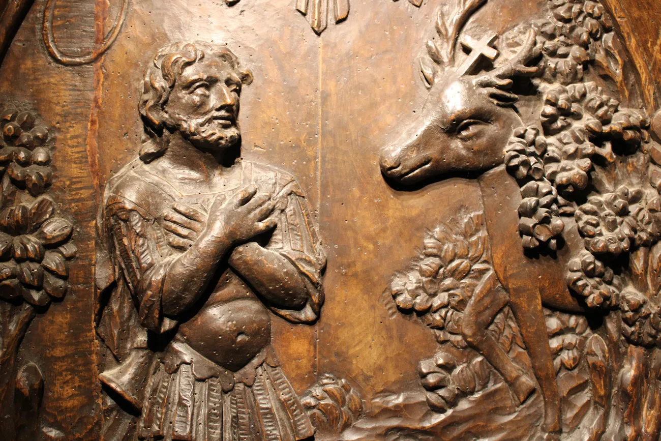 Médaillon en bois sculpté du XVIIIe siècle représentant la vision de Saint Hubert dans un cadre baroque. Ⓒ 2026 CC BY-NC 4.0 Gilles Pirlot de Corbion