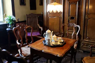 La chambre derrière le feu de la Blanche Maison expose une grande armoire avec horloge centrale qui provient de l’ancien hôtel d’Orange à Stavelot ainsi qu’une table et quatre fauteuils de style Régence liégeois Ⓒ 2025 CC BY-NC 4.0 Didier Misson