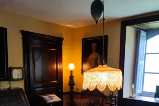 Douce lumière provenant d’une ancienne lampe à huile, aujourd’hui électrifiée, dans la chambre derrière le feu de la Blanche Maison Ⓒ 2025 CC BY-NC 4.0 Didier Misson