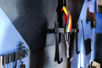 La crémaillère, provenant du petit village ardennais de Regné, est suspendue dans la cuisine de la Blanche Maison. Ⓒ 2025 CC BY-NC 4.0 Didier Misson La crémaillère du XVIIe siècle originaire de Regné arbore fièrement les couleurs nationales dans la cuisine de la Blanche Maison