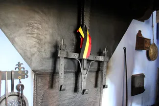 Rare crémaillère ardennaise du XVIIe siècle à trois crochets ornés de fleurs de lys, portant encore le ruban de l’inauguration, suspendue dans la cheminée de la Blanche Maison Ⓒ 2025 CC BY-NC 4.0 Didier Misson