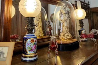 Vierge Marie portant l’Enfant Jésus,  lampes en porcelaine émaillée bleue décorée de motifs floraux peints et chevaux en verre soufflé avec un corps rouge rubis posés sur un meuble en chêne du XVIIIe siècle dans la belle salle de la Blanche Maison Ⓒ 2025 CC BY-NC 4.0 Didier Misson