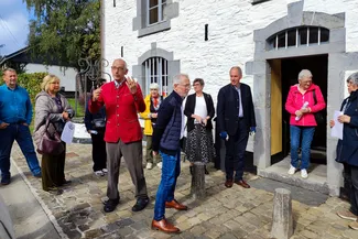 Les invités à l'inauguration entourent Gilles Pirlot de Corbion et Jean-Pierre Dardenne lors de l'inauguration. Ⓒ 2025 CC BY-NC 4.0 Didier Misson Gilles Pirlot de Corbion parle aux invités devant la porte d'entrée de la Blanche Maison