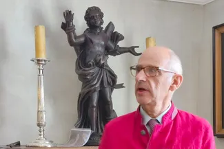 La Sagittation de Saint Sébastien, œuvre de Jean-Georges Scholtus, représente le martyre du saint patron des archers. Ⓒ 2025 CC BY-NC 4.0 Didier Misson Gilles Pirlot de Corbion devant la Sagittation de Saint Sébastien, une statue en chêne foncé sculptée par Jean-Georges Scholtus aux alentours de 1725