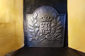 Taque de cheminée en fonte, au fond du placard de taque, arborant les armes de la famille Pirlot de Corbion avec sa devise IN ORDINE Ⓒ 2025 CC BY-NC 4.0 Didier Misson