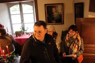 Vue en plongée de la belle salle de la Blanche Maison, où les participants au goûter de Noël évoluent librement dans l'espace muséal.