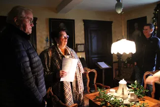 Sur la table de la chambre derrière le feu de la Blanche Maison, un service en porcelaine blanche est disposé sur un napperon de dentelle agrémenté de branches de houx frais.