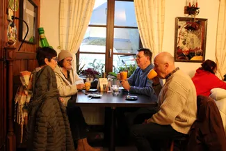 Dans la taverne Le Rustique à Nisramont, quatre participants au goûter de Noël sont installés autour d'une table près de la fenêtre.