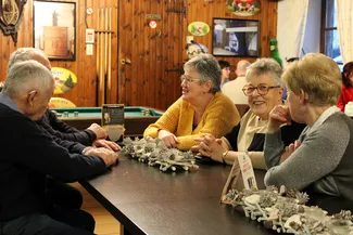 Les tables de la taverne Le Rustique sont décorées avec des pommes de pin givrées, des petits cœurs blancs découpés et des étoiles sur un assemblage de petits rondins de bois écorcés et blanchis.