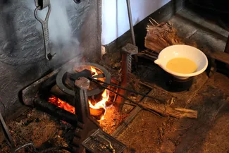 Quand la pâte est dans les fers à oublies, la cuisson commence dans l'âtre de la cheminée