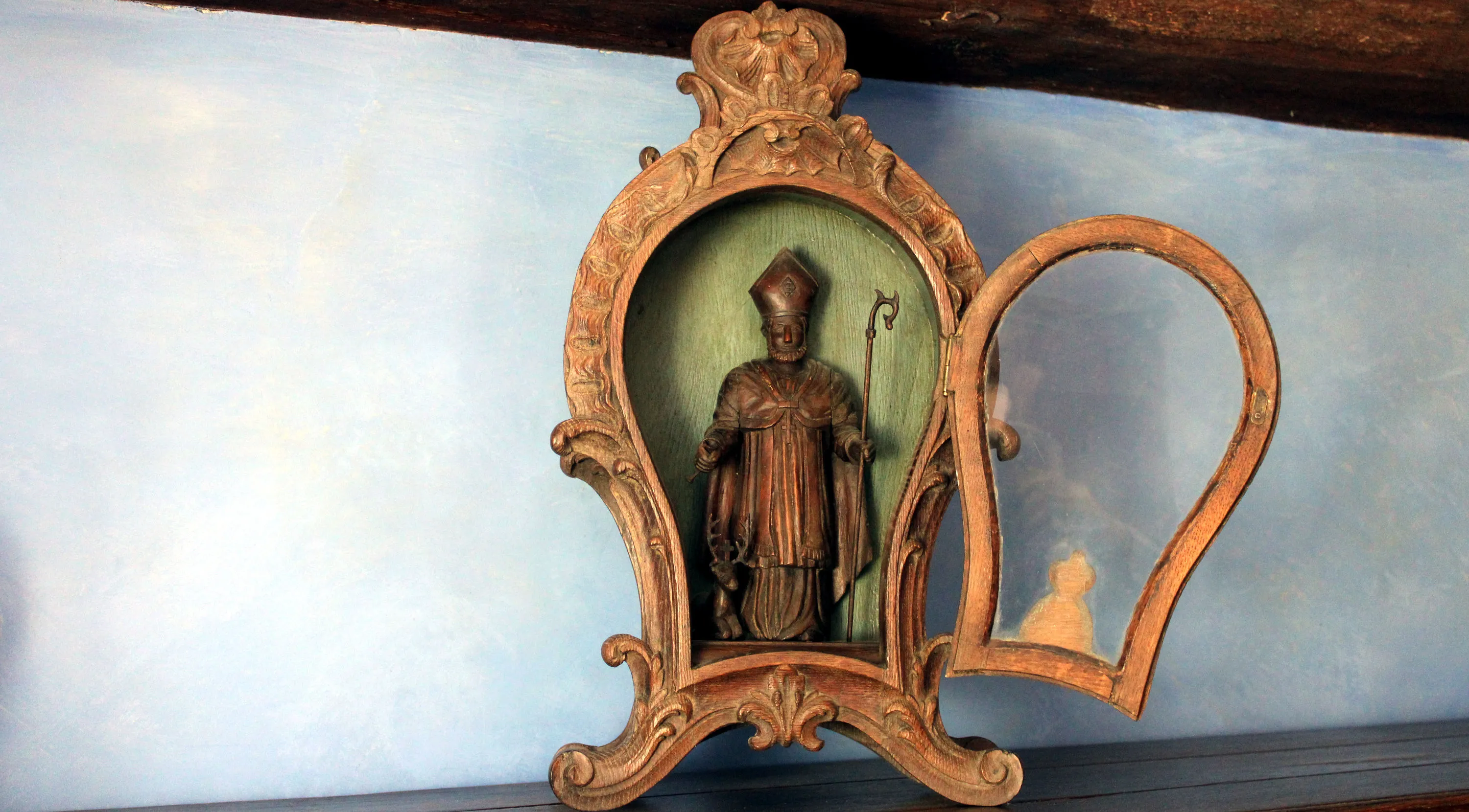 Niche vitrée de forme violonée datant du XIXe siècle, décorée de sculptures de style rocaille, contenant une statue de Saint Hubert accompagnée de son cerf crucifère. Ⓒ 2024 CC BY-NC 4.0 Gilles Pirlot de Corbion