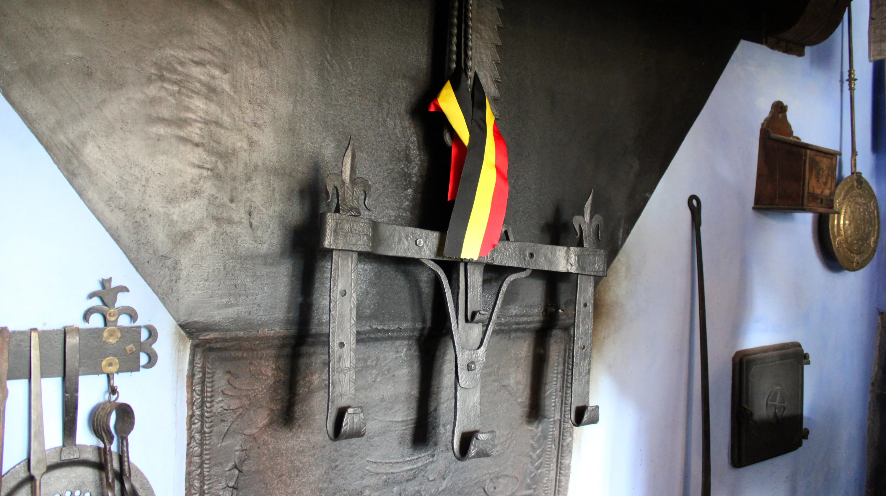 Rare crémaillère ardennaise du XVIIe siècle à trois crochets ornés de fleurs de lys, portant encore le ruban de l’inauguration, suspendue dans la cheminée de la Blanche Maison le 13 septembre 2025. Ⓒ 2025 CC BY-NC 4.0 Didier Misson