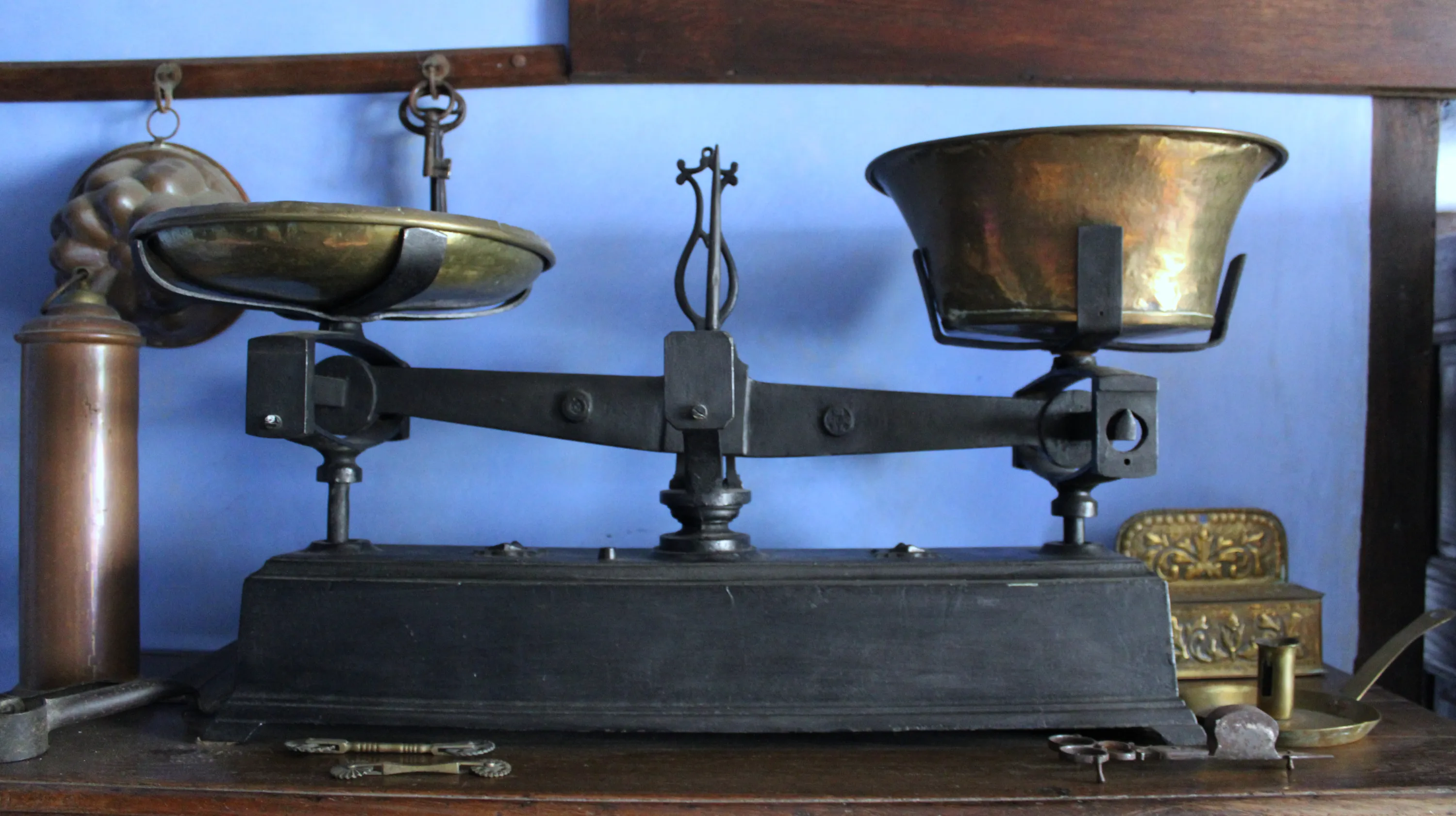 Balance Roberval à plateaux, avec un socle en fonte de fer munie de deux récipients en laiton martelé au un pivot central orné d’un élégant motif en forme de lyre, exposée dans la cuisine de la Blanche Maison comme instrument de pesée domestique utilisé au XIXe siècle  Ⓒ 2025 CC BY-NC 4.0 Gilles Pirlot de Corbion