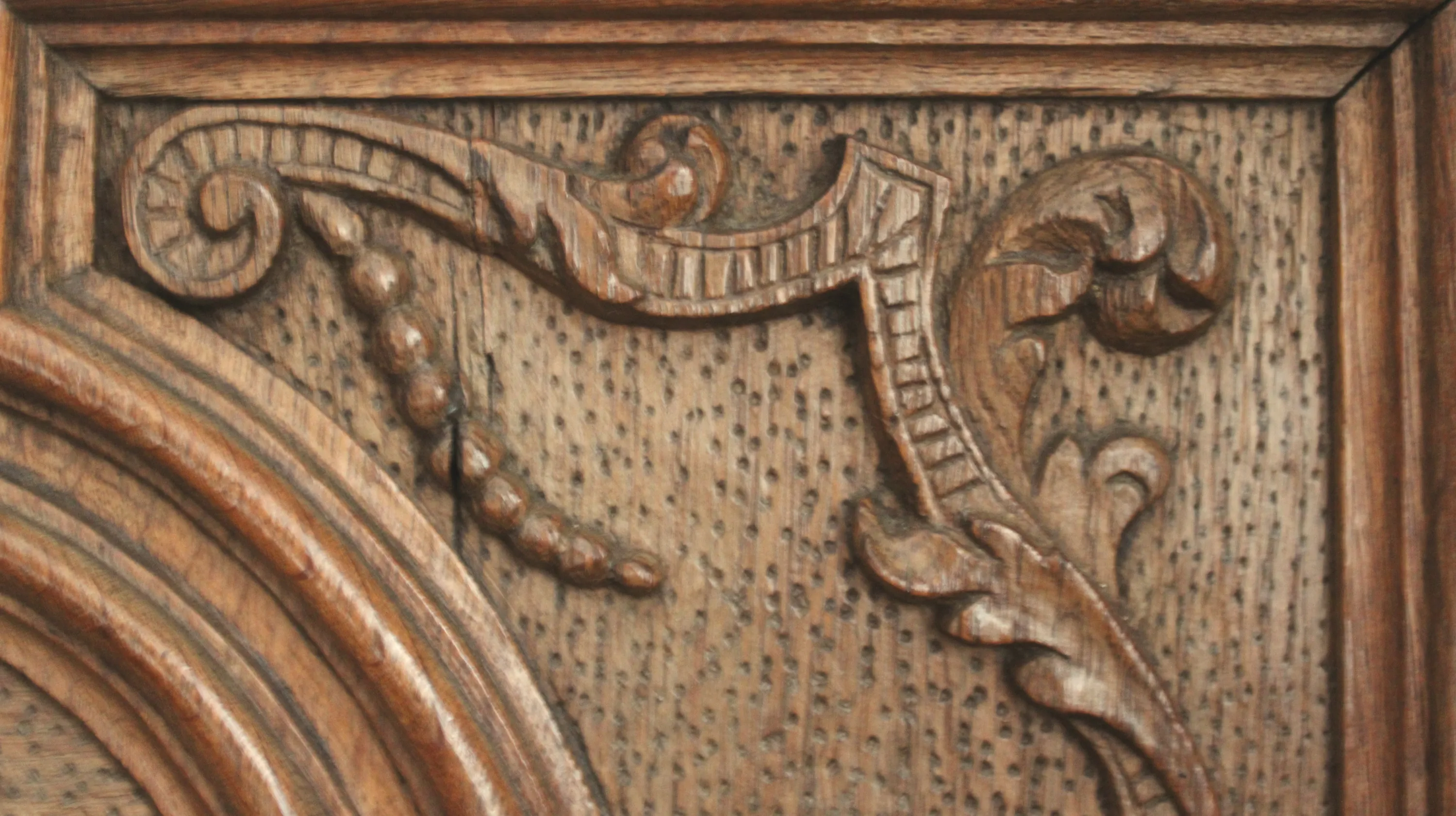 Panneau supérieur droit du meuble à abattant attribué au maître menuisier et sculpteur Jean-Georges Scholtus décoré d’une volute striée avec feuilles d’acanthe et tige perlée de style Louis XIV sur un fond piqueté. Ⓒ 2026 CC BY-NC 4.0 Gilles Pirlot de Corbion