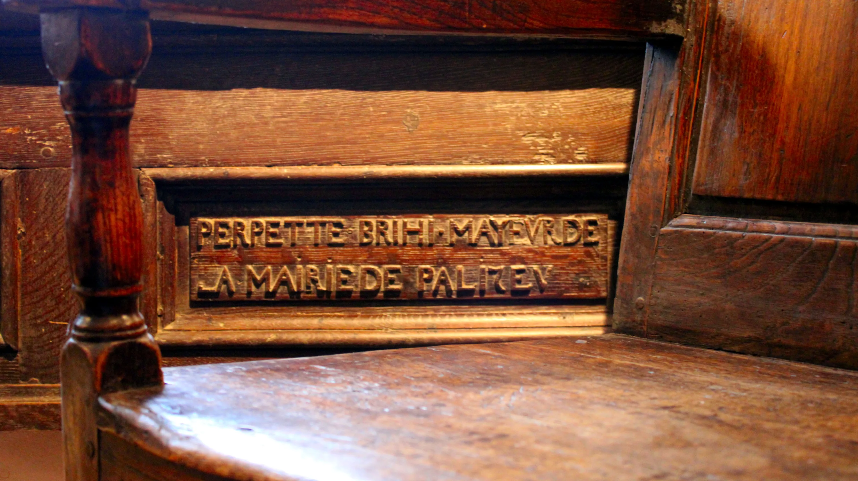 Nom du mayeur de Paliseul, qui exerça la fonction d’officier de justice et d'administration entre 1670 et 1690, sculpté en lettres capitales romaines dans un panneau de bois massif qui surmontait jadis les stalles de l'ancienne église de Paliseul, détruite au début du XXe siècle, exposé dans la salle Saint-Hubert de la Blanche Maison. Ⓒ 2026 CC BY-NC 4.0 Gilles Pirlot de Corbion