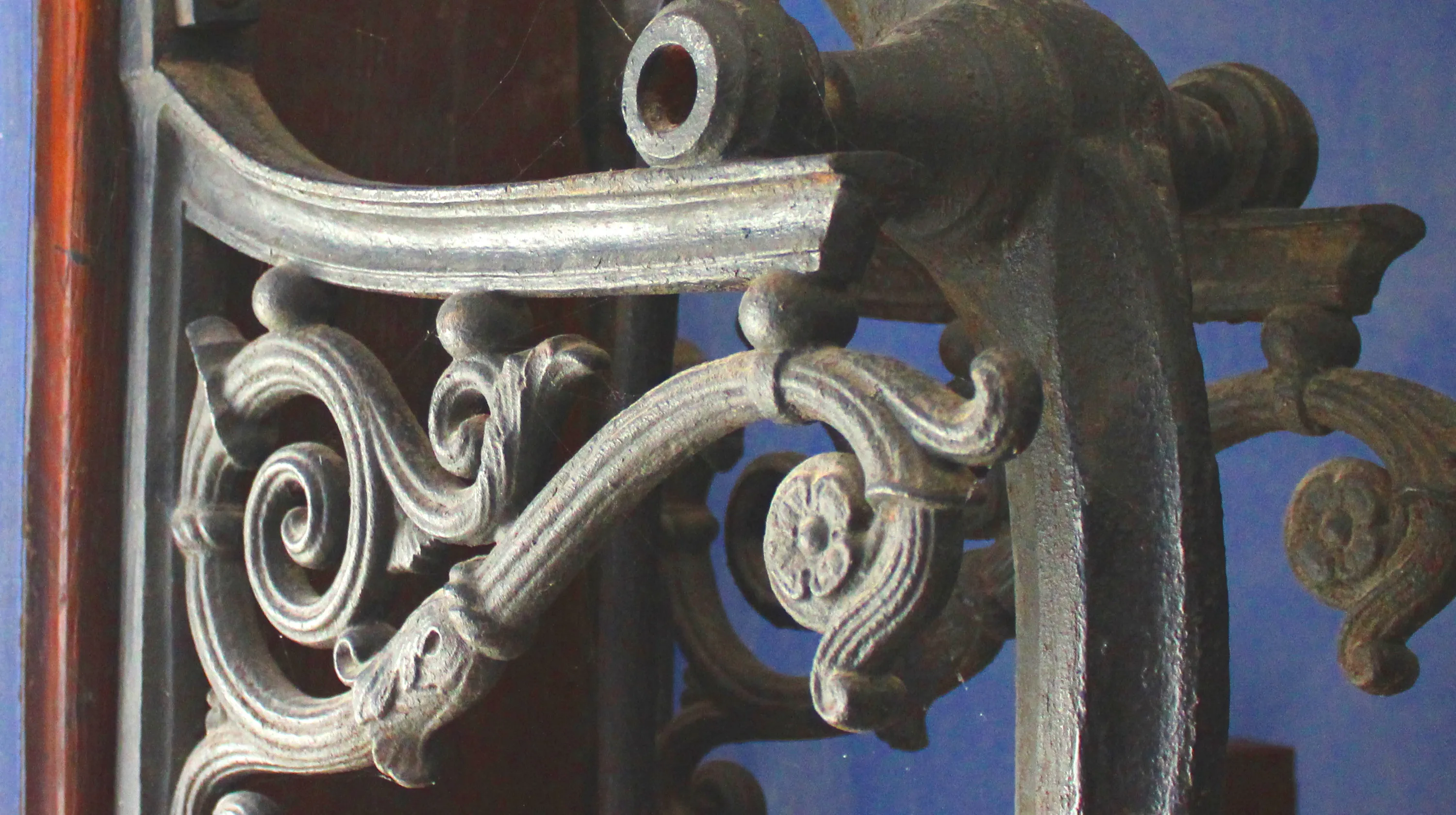 Partie supérieure d'un mécanisme de pompe à eau en fonte datant du XIXe siècle, exposé dans la cuisine de la Blanche Maison, dont la potence en ferronnerie déploie un jeu de volutes agrémentées de délicats motifs floraux, dont une petite rosette à quatre pétales, témoignant ainsi d'une époque où l'esthétique sublimait les objets les plus utilitaires de la vie domestique. Ⓒ 2026 CC BY-NC 4.0 Gilles Pirlot de Corbion